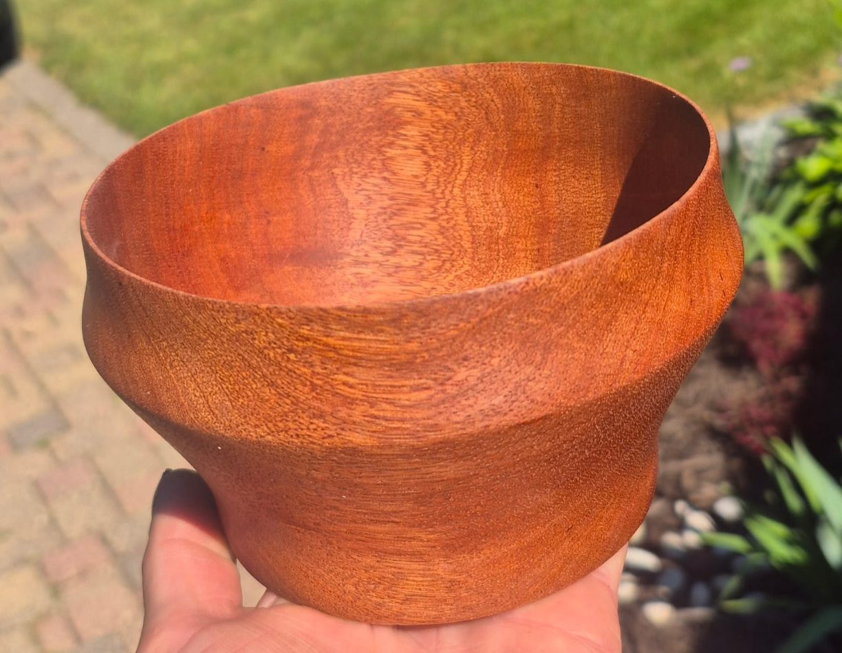 A turned sapele bowl held in one hand