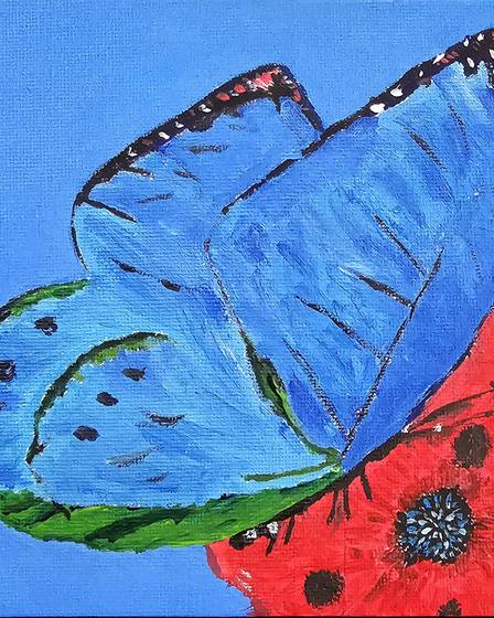 A painted blue butterfly on a red and green ground