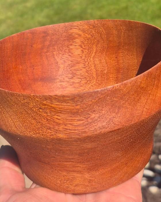 A turned sapele bowl held in one hand