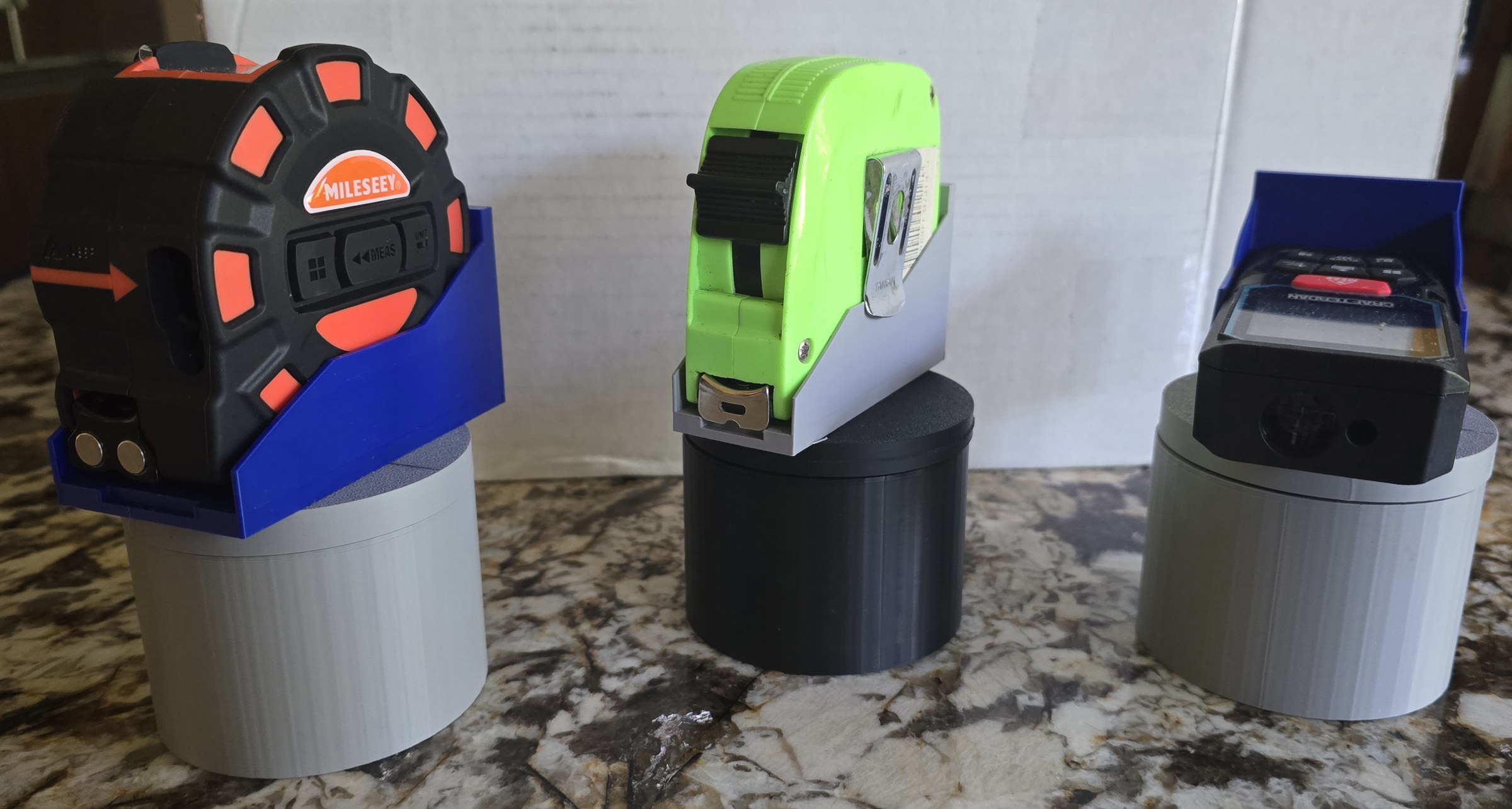 Individual holders for tape measures and a digital measuring tool.